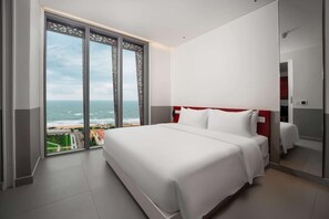 A hotel room with a large bed, a view of the ocean, and a red accent wall. - Wink Hotel Tuy Hoa Beach (Tuy Hoa)