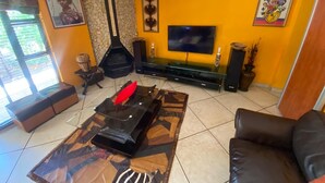 A living room with a fireplace, a flat-screen TV, and a sofa. - Charming 2-bedroom estate with fitness room in Woodland Hills Estate (Woodland Hills Estate, Bloemfontein)