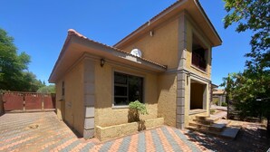 A two-story house with a tiled driveway and a small garden. - Charming 2-bedroom estate with fitness room in Woodland Hills Estate (Woodland Hills Estate, Bloemfontein)