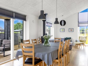 Ein Essbereich mit einem runden Tisch, Holzstühlen und Pendelleuchten.