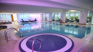 Une piscine intérieure dotée d’un jacuzzi circulaire, de chaises longues et d’un espace dédié au bronzage.