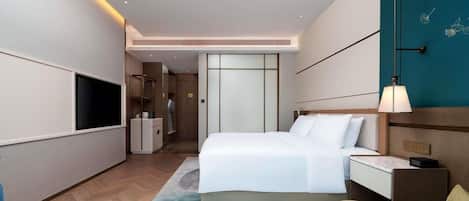 A modern hotel room with a large bed, bedside table, and a flat-screen TV.
