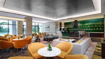 A modern hotel lobby with seating areas, a bar, and large windows.