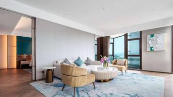 A modern living room with a sofa, armchairs, a coffee table, and a large window offering a view.