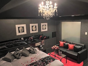 Habitación de hotel moderna con una cama grande, un sofá, un espejo y una araña.