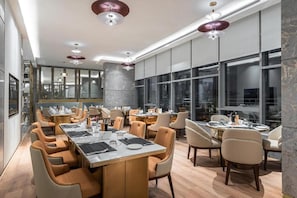 A modern dining area with multiple tables and chairs, large windows, and contemporary lighting fixtures. - Braira Abha Hotel (Abha)
