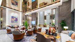 Un hall amplio con mobiliario moderno, un televisor de pantalla plana y plantas decorativas.