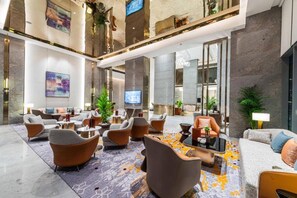 A spacious lobby with modern furniture, a flat-screen TV, and decorative plants. - Braira Abha Hotel (Abha)