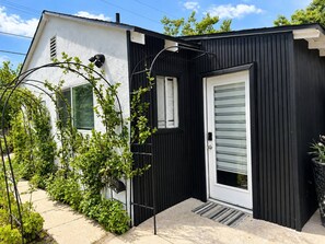 A modern house with a black exterior, white door, and a small porch area. - Secret Valley Guest House | Cozy & Private 1BR (Los Angeles)