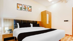 A modern hotel room with a large bed, a wooden headboard, a nightstand with a lamp, and a wall-mounted air conditioning unit. - Townhouse Oak Walmi Govindpur (Danapur)