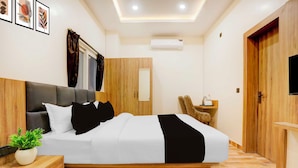 A modern bedroom with a bed, bedside tables, a TV, and a wardrobe. - Townhouse Oak Walmi Govindpur (Danapur)