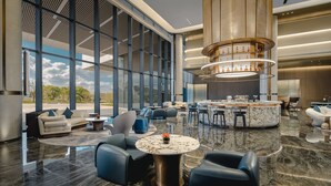 A spacious lobby with a marble floor, a central seating area with sofas and chairs, a bar with a circular marble countertop, and large windows offering a view of the outdoors. - Holiday Inn Kunshan East (Suzhou)