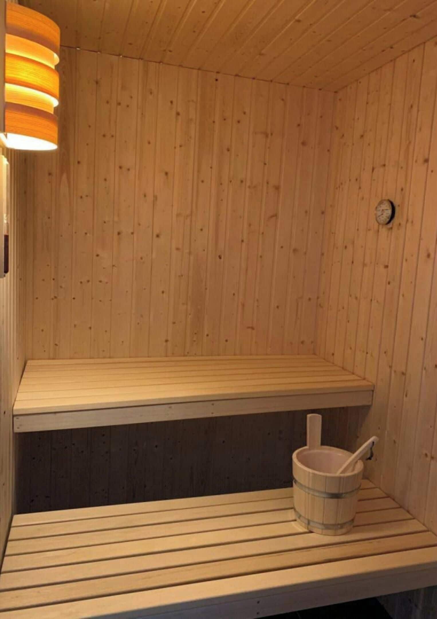A wooden sauna with a bench and a bucket.