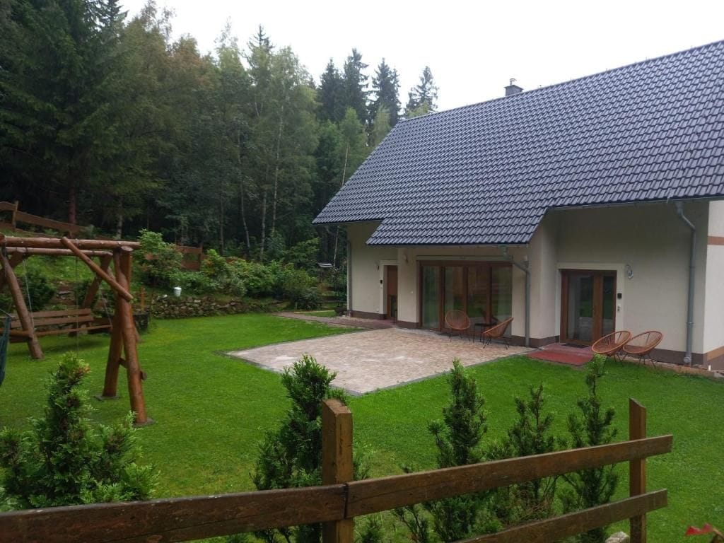 A house with a tiled roof, a paved patio, and a fenced yard.