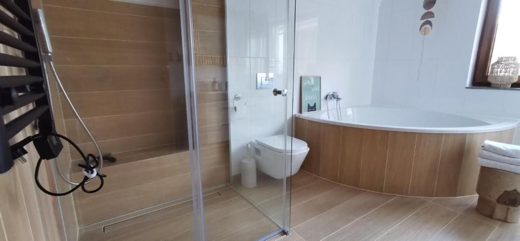 A modern bathroom with a glass shower enclosure, a freestanding toilet, and a freestanding bathtub.