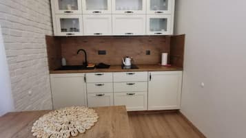 A kitchen with white cabinets, a wooden countertop, and a sink.