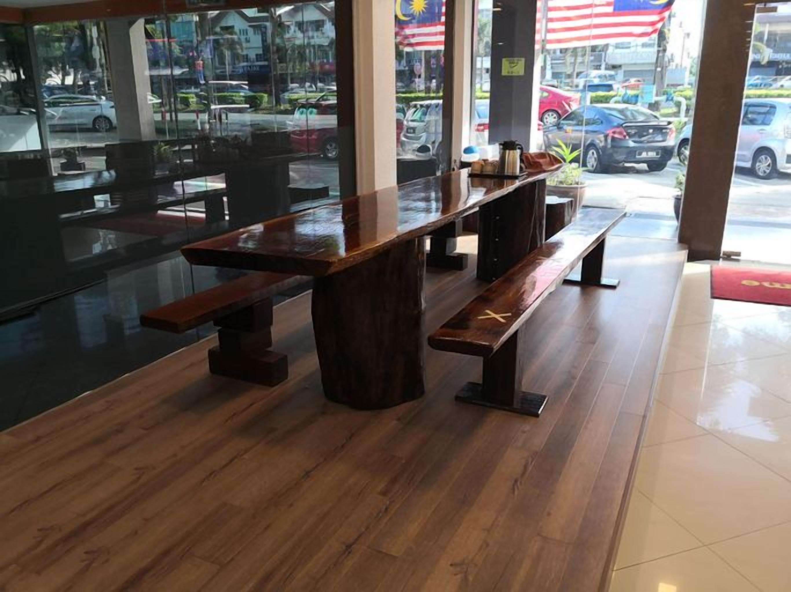 A restaurant interior with wooden tables and benches, large windows, and a view of the street outside.