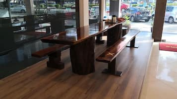 A restaurant interior with wooden tables and benches, large windows, and a view of the street outside.