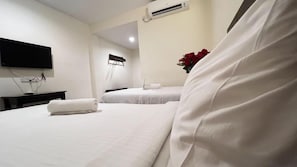 A hotel room with two beds, a flat-screen TV mounted on the wall, an air conditioning unit, and a vase with red flowers on the nightstand. - Chariton Skudai Hotel (Johor Bahru)