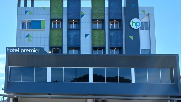 Un edificio moderno de hotel con un llamativo letrero que dice 'hotel premier' y un logotipo con las letras 'hp' en la fachada.