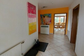 A hallway with a radiator, a black mat, a white cabinet, and a painting on the wall. - Holiday apartment with 4 bedrooms (Cuxhaven)