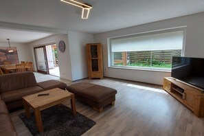 A modern living room with a sofa, ottoman, coffee table, and a television on a wooden stand. - Holiday apartment with 4 bedrooms (Cuxhaven)