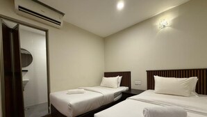 Habitación de hotel con dos camas, ducha y aire acondicionado.