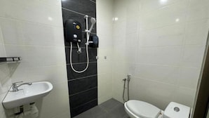 Un baño con un lavamanos blanco, un inodoro y una ducha con panel de control.
