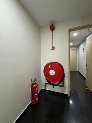 A hallway with a fire extinguisher and a red fire hose reel mounted on the wall. - Ibilik Hotel @ Johor Bahru (Johor Bahru)