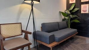 Un área de espera moderna con un sofá, una silla, una lámpara de pie y obras de arte enmarcadas en la pared.