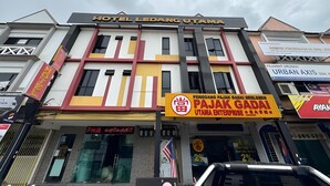 Un hotel con un letrero que dice 'HOTEL LEDANG UTAMA' y un llamativo letrero de 'PAJAK GADAI UTAMA ENTERPRISE'.