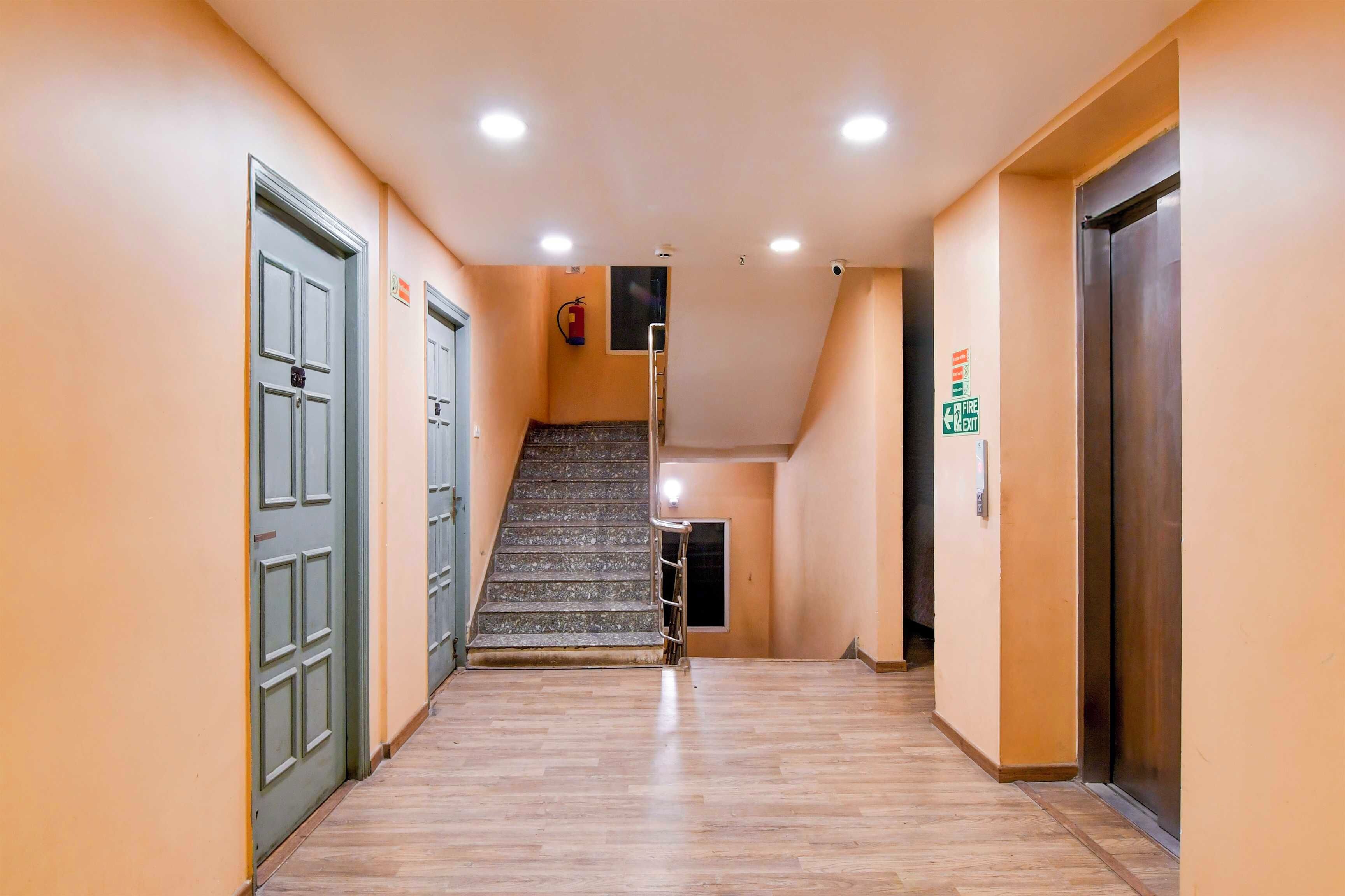 Un pasillo con suelo de madera, una escalera y puertas a ambos lados.