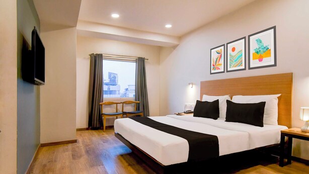 Una habitación de hotel con una cama, un escritorio, una silla, un televisor y una ventana con cortinas.