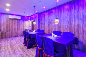A conference room with tables covered in blue cloths, chairs, and a wooden wall. - Townhouse Oak Kolkata Tegharia Bus Stand (Barasat)
