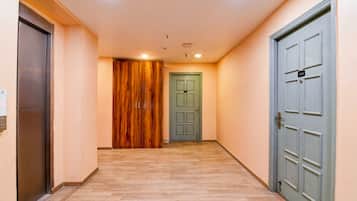 A hallway with wooden flooring, a green door, and a grey door with a number plate.