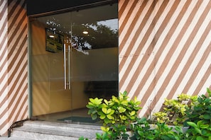 Une entrée moderne avec une porte en verre et un mur extérieur à rayures.