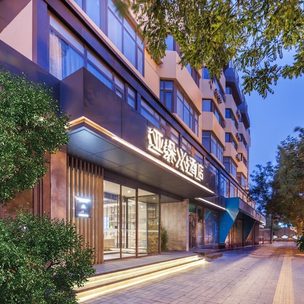 A modern hotel building with a prominent sign, large windows, and a well-lit entrance. - Atour X Hotel, Majiabao Metro Station, Beijing South Railway Station (Beijing)