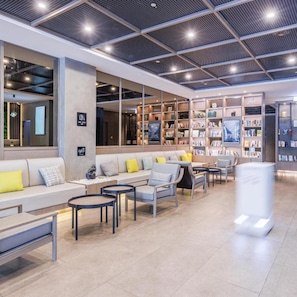 A modern library with seating areas, bookshelves, and a ceiling with a grid pattern. - Atour X Hotel, Majiabao Metro Station, Beijing South Railway Station (Beijing)