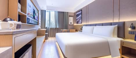 A modern hotel room with a large bed, a desk with a flat-screen TV, a coffee station, and a view of the outdoors.