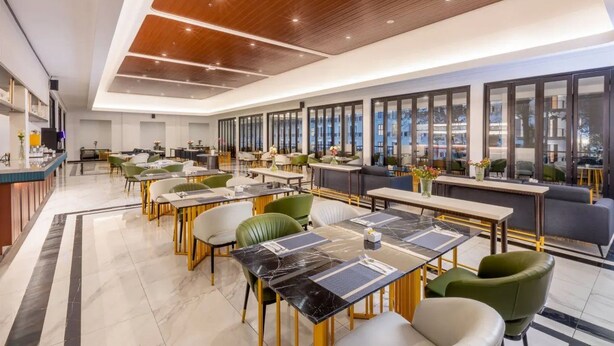 Een modern restaurant met een lange toonbank, meerdere eettafels en stoelen.