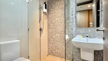 A modern bathroom with a glass-enclosed shower, a white toilet, and a sink with a marble backsplash.