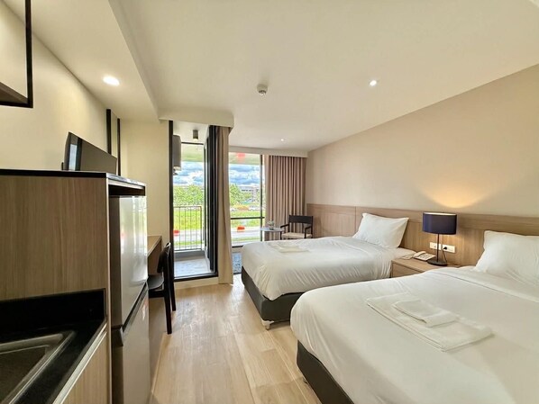 A hotel room with two beds, a desk, a chair, a TV, and a balcony with a view. - Rangsit Residence & Hotel (Thanyaburi)