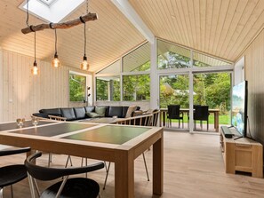 Un vaste espace de vie comprenant une grande table en bois, des chaises noires et un canapé en cuir noir.