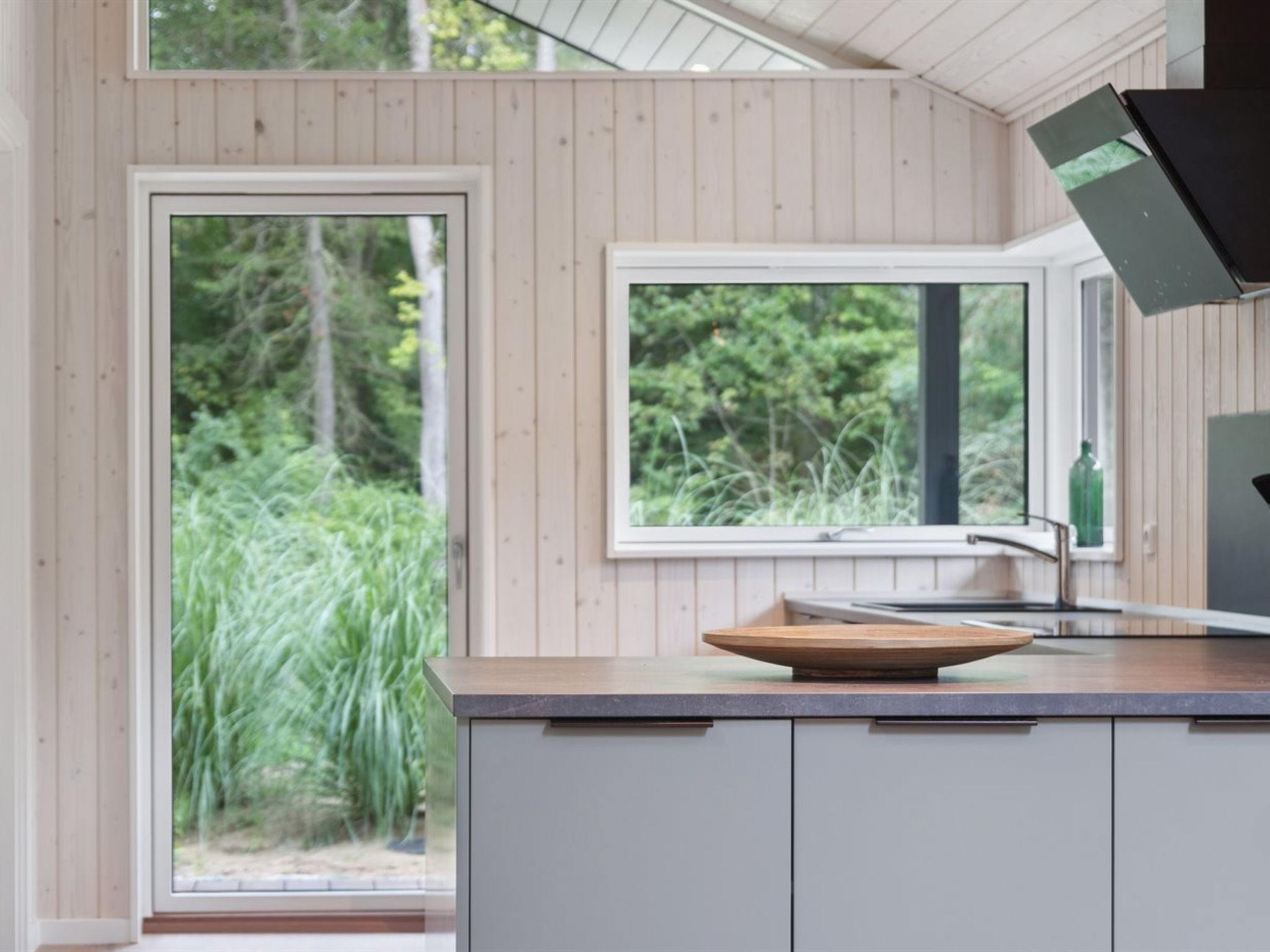 Une cuisine moderne dotée d’une grande fenêtre, de meubles en bois et d’un évier en cuve.