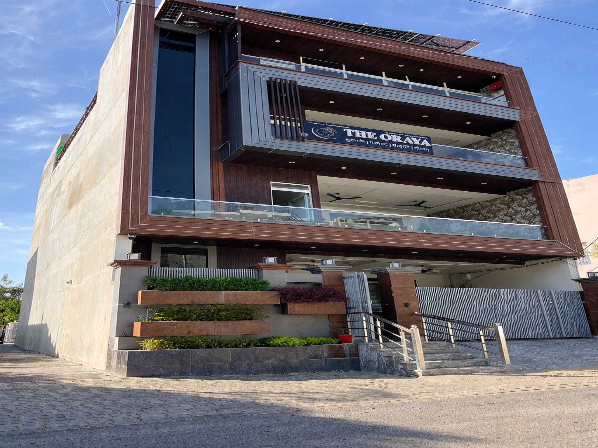 Un edificio moderno con un letrero que dice 'THE ORAYA' hotel. Tiene una estructura de dos pisos con un balcón en el piso superior.