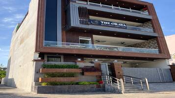 Un edificio moderno con un letrero que dice 'THE ORAYA' hotel. Tiene una estructura de dos pisos con un balcón en el piso superior.