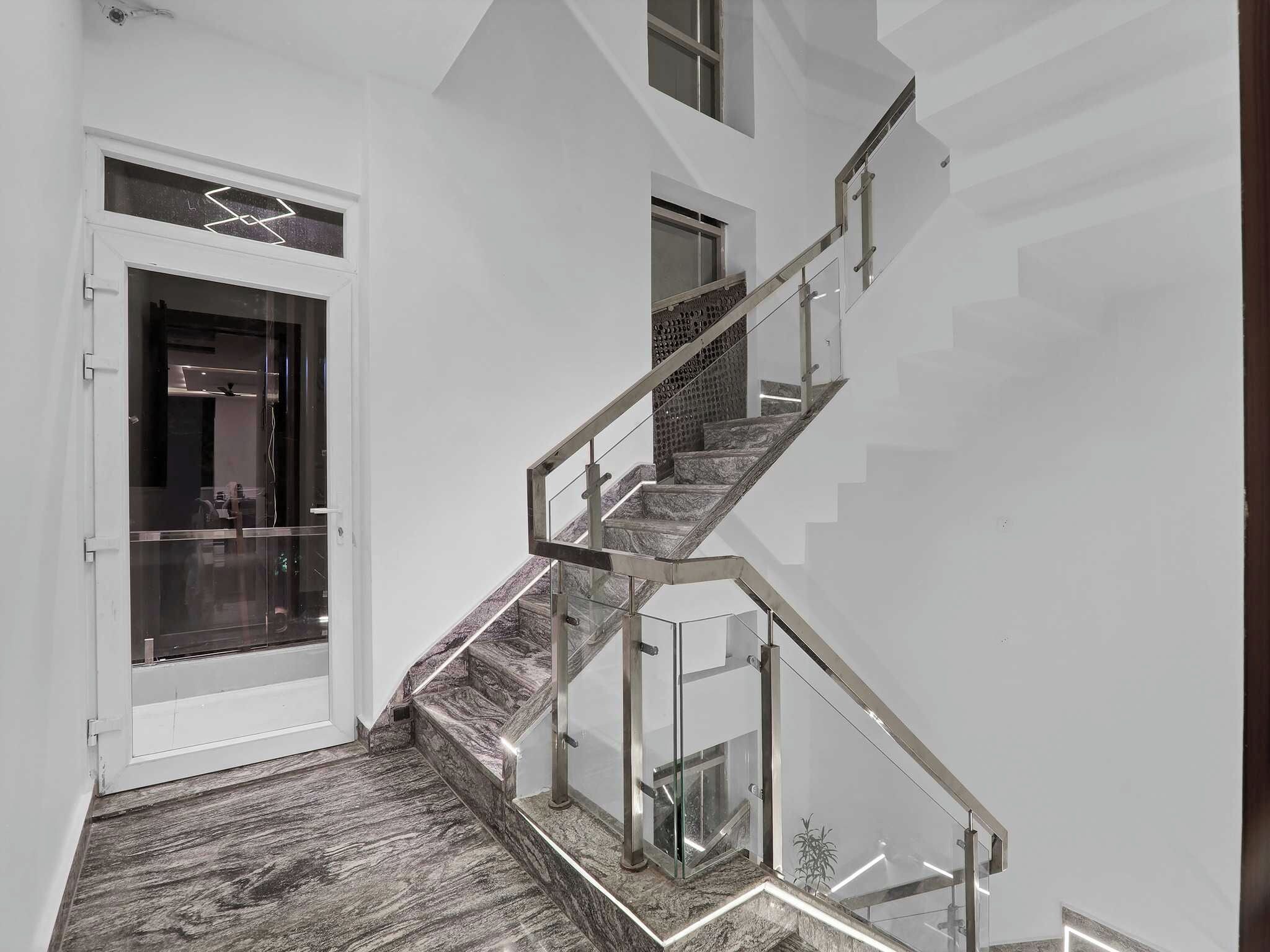 Una escalera moderna con barandas de vidrio y piso de madera.