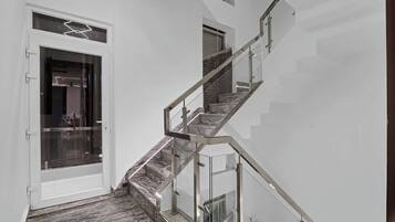 Una escalera moderna con barandas de vidrio y piso de madera.