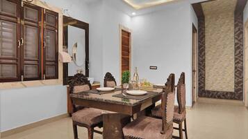 Un comedor con una mesa de mármol, sillas de madera, un espejo grande y una puerta decorativa.