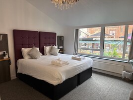 A modern bedroom with a large bed, a dark headboard, and a view of the outside.